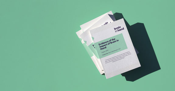 Graphic of a set of books and papers with the cover title reading "Evidence of the impact of Brain in Hand" on a green background. 